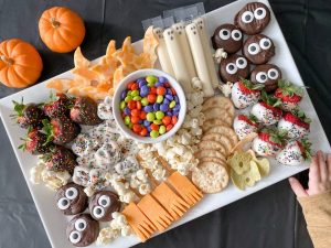 Halloween charcuterie board with child's hand reaching for treat