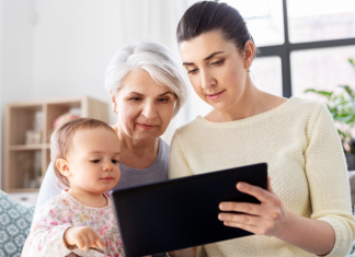 the sandwich generation: daughter with child and grandmother on couch looking at tablet