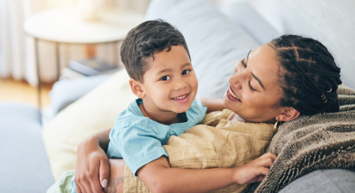 mother and son hugging and smiling on gray couch